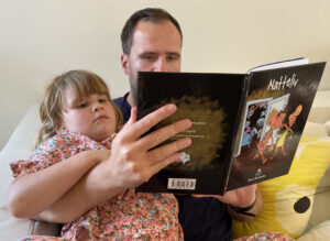 René Birkholms søn, Benjamin, læser højt fra børnebogen Natteliv for barnebarnet Elli.